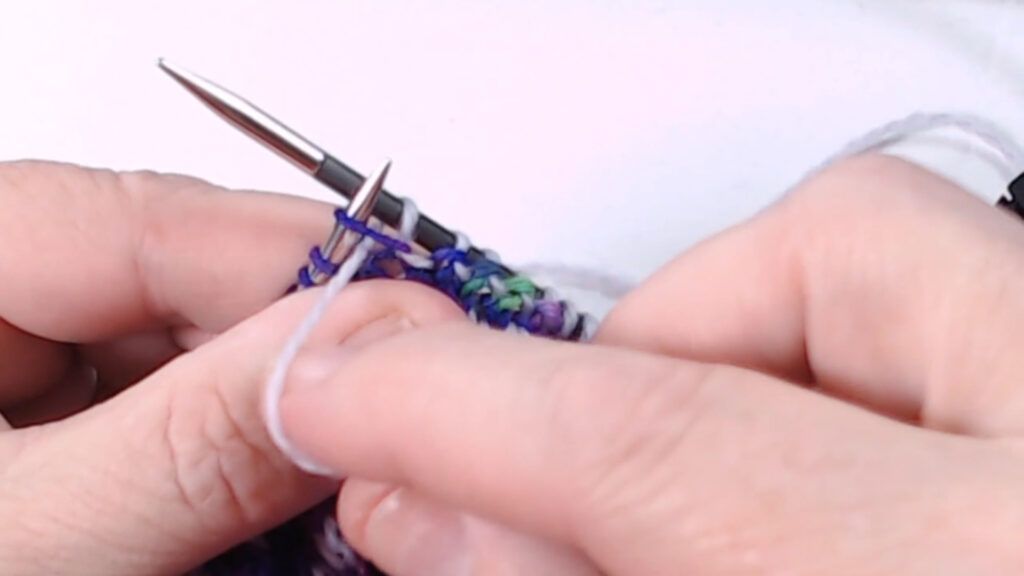needle inserted into purl stitch below